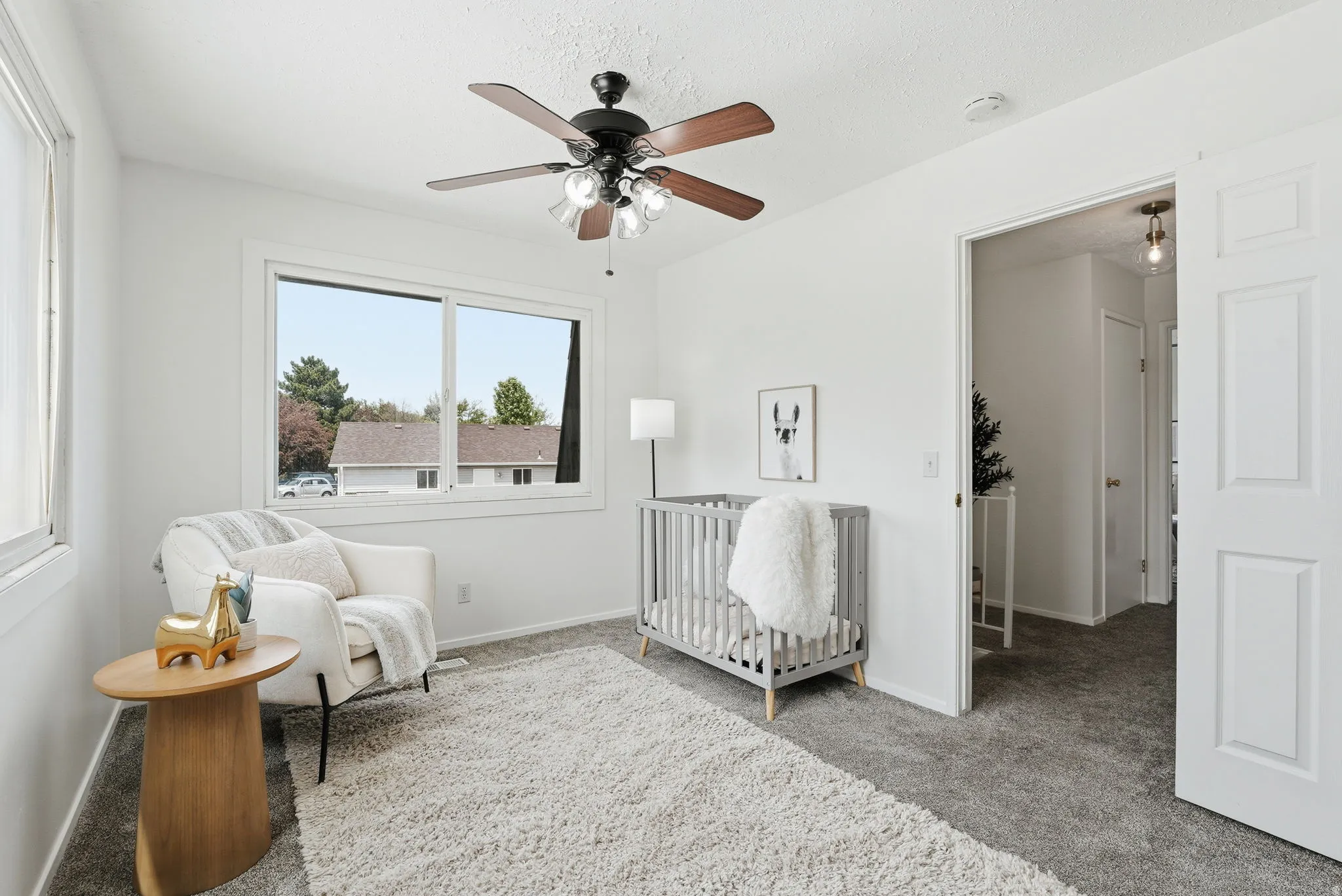 Bedroom with a nursery area, light carpet, and a ceiling fan