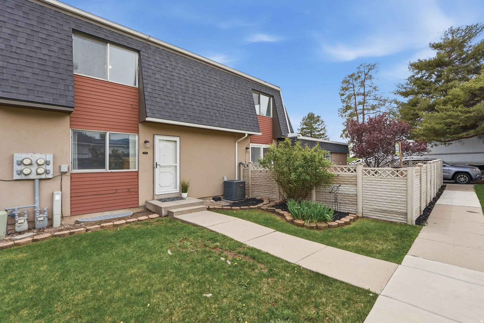 View of front facade with roof with shingles, mansard roof, and stucco siding