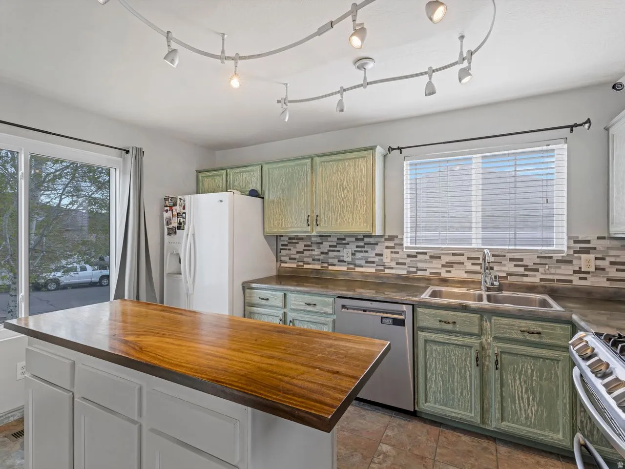 Kitchen featuring green cabinets, stainless steel appliances, plenty of natural light, and wood counters