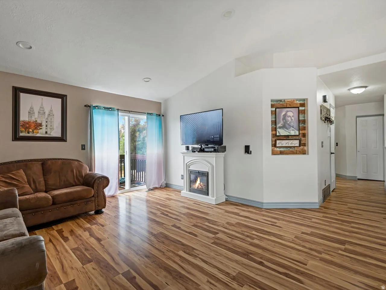 Living area featuring lofted ceiling, wood finished floors, and a glass covered fireplace