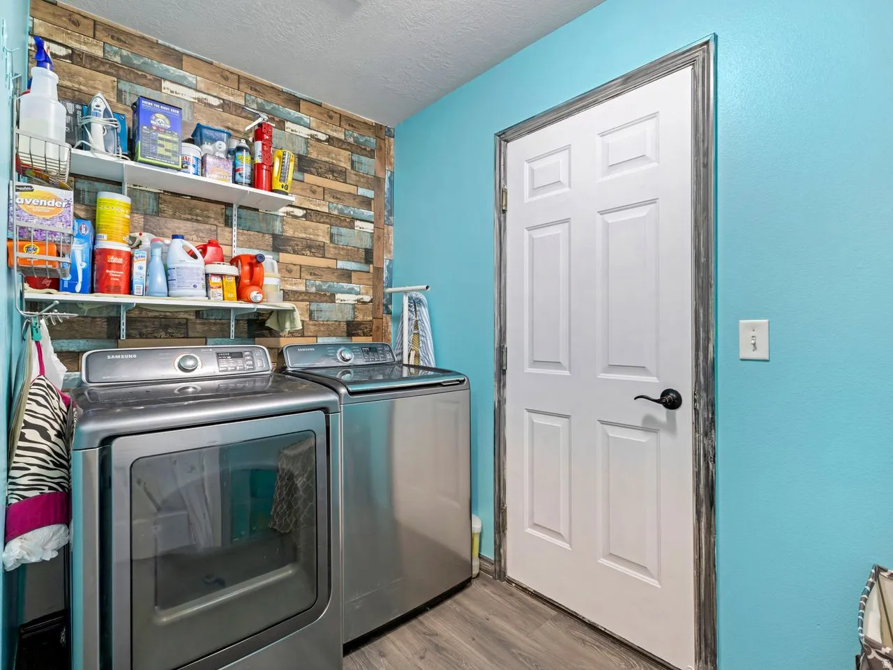 Laundry area with light wood-style floors, a textured ceiling, and washing machine and clothes dryer