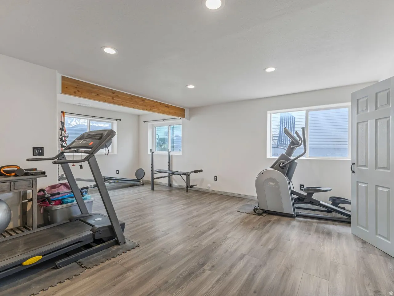 Workout room featuring light wood-style floors, recessed lighting, and beamed ceiling