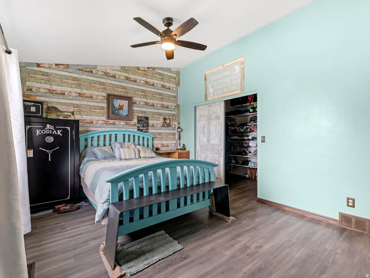 Bedroom with an accent wall, wood finished floors, vaulted ceiling, ceiling fan, and a closet