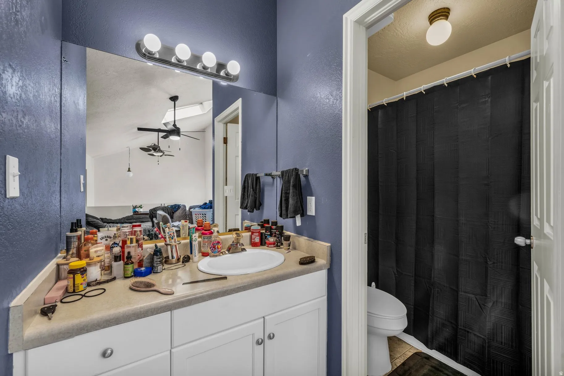 Full bath with a textured wall, vanity, a shower with curtain, ceiling fan, and a textured ceiling