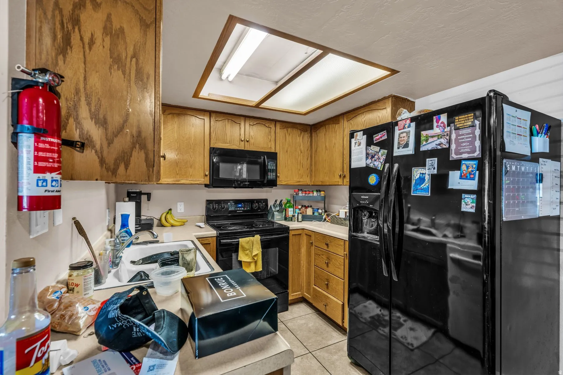Kitchen featuring black appliances, light countertops, and wood finish cabinets