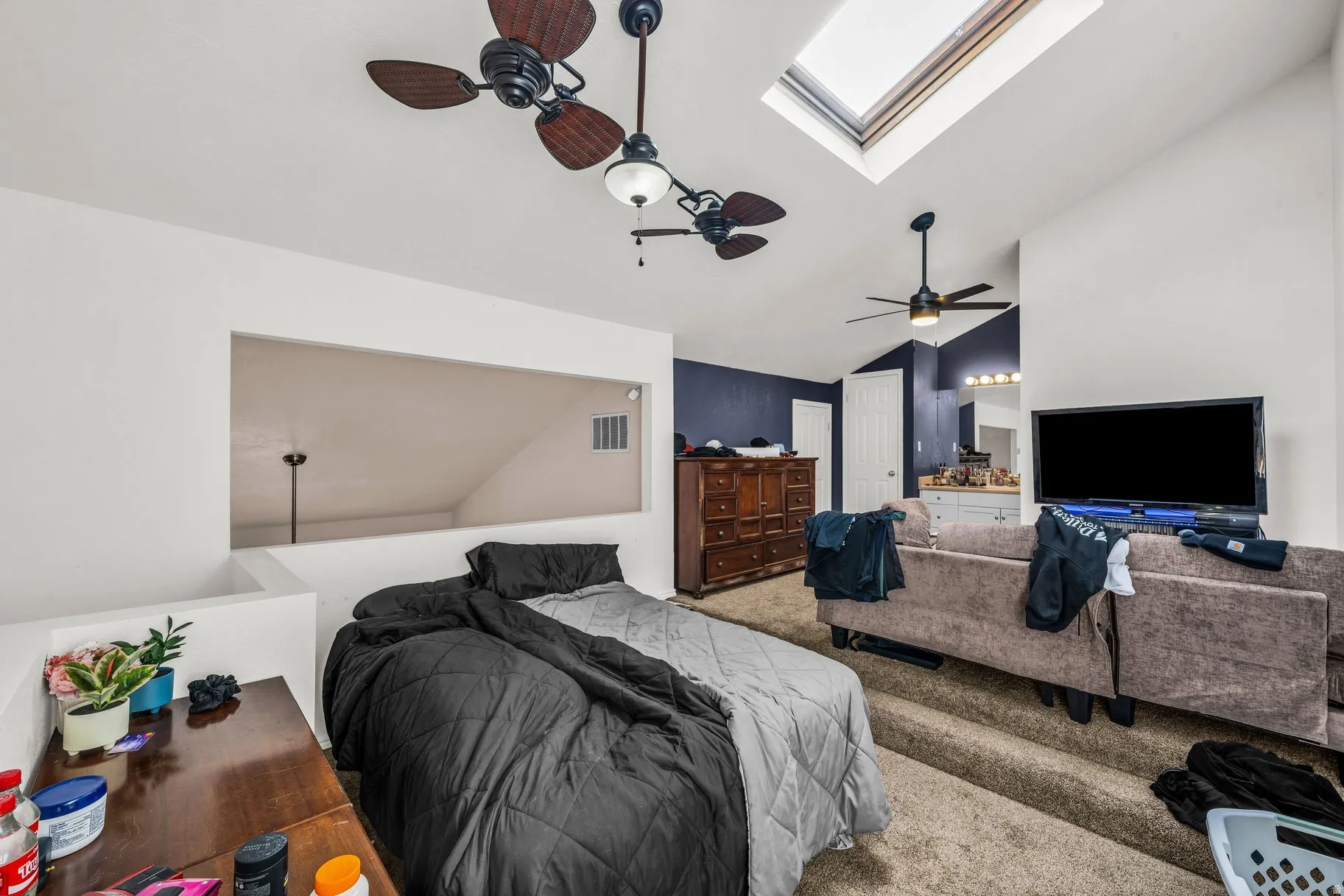 Bedroom with a skylight, lofted ceiling, carpet floors, ensuite bath, and ceiling fan