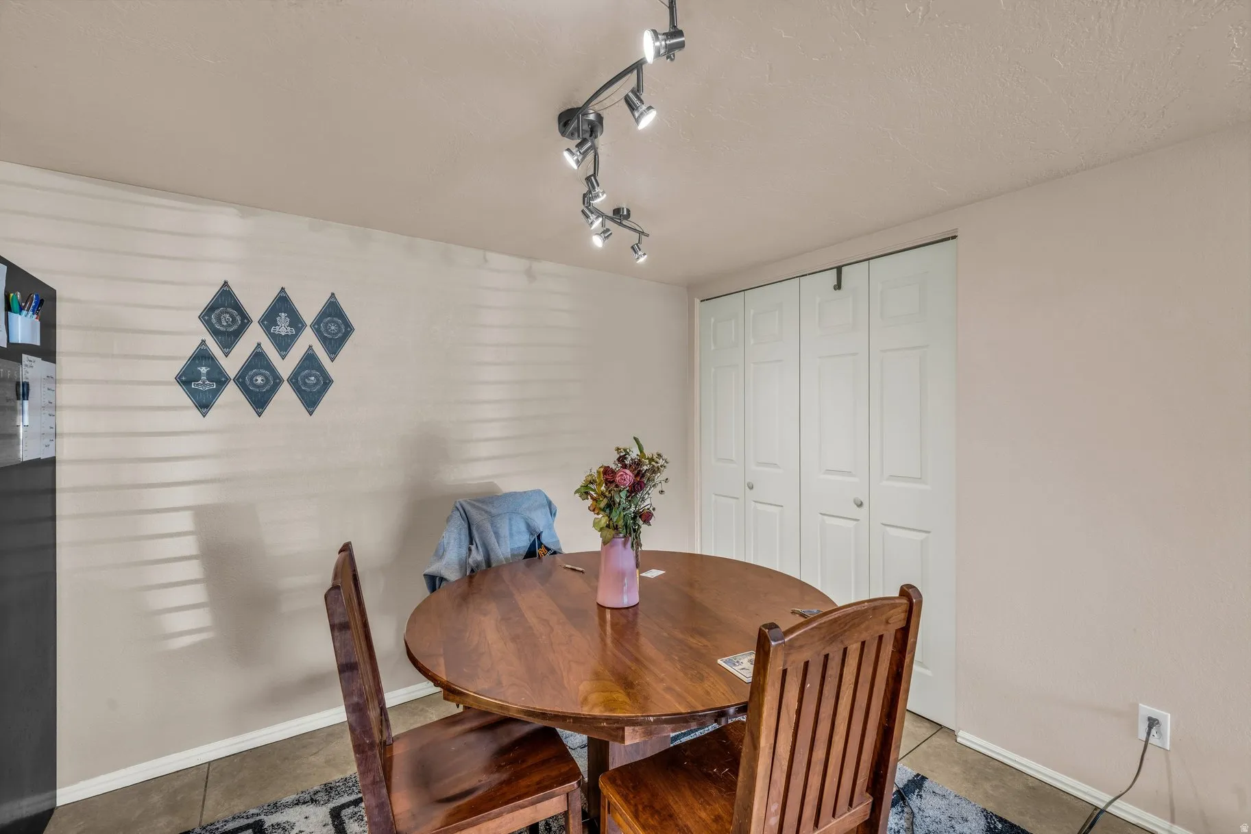 Tiled dining space featuring rail lighting and a textured ceiling