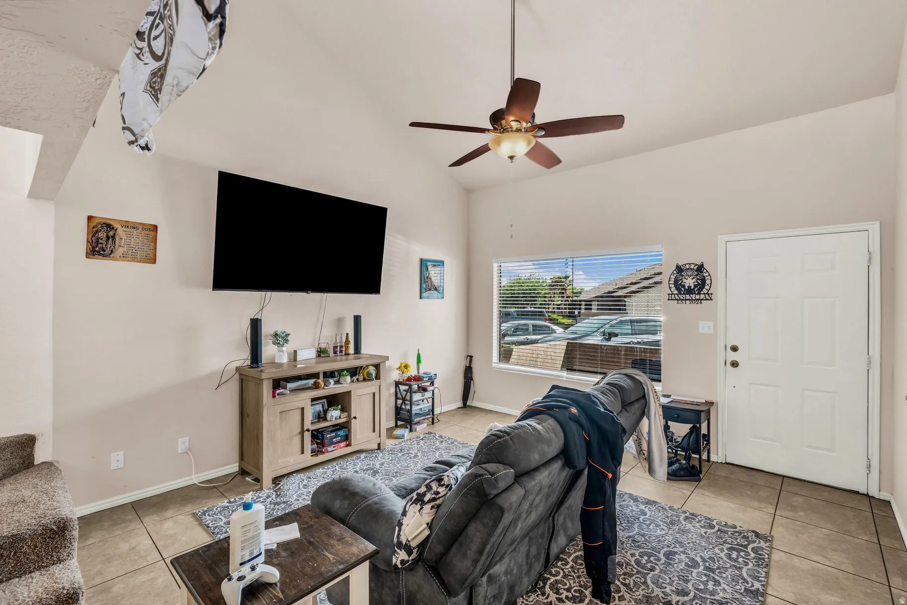 Living room featuring light tile patterned floors, vaulted ceiling, and ceiling fan