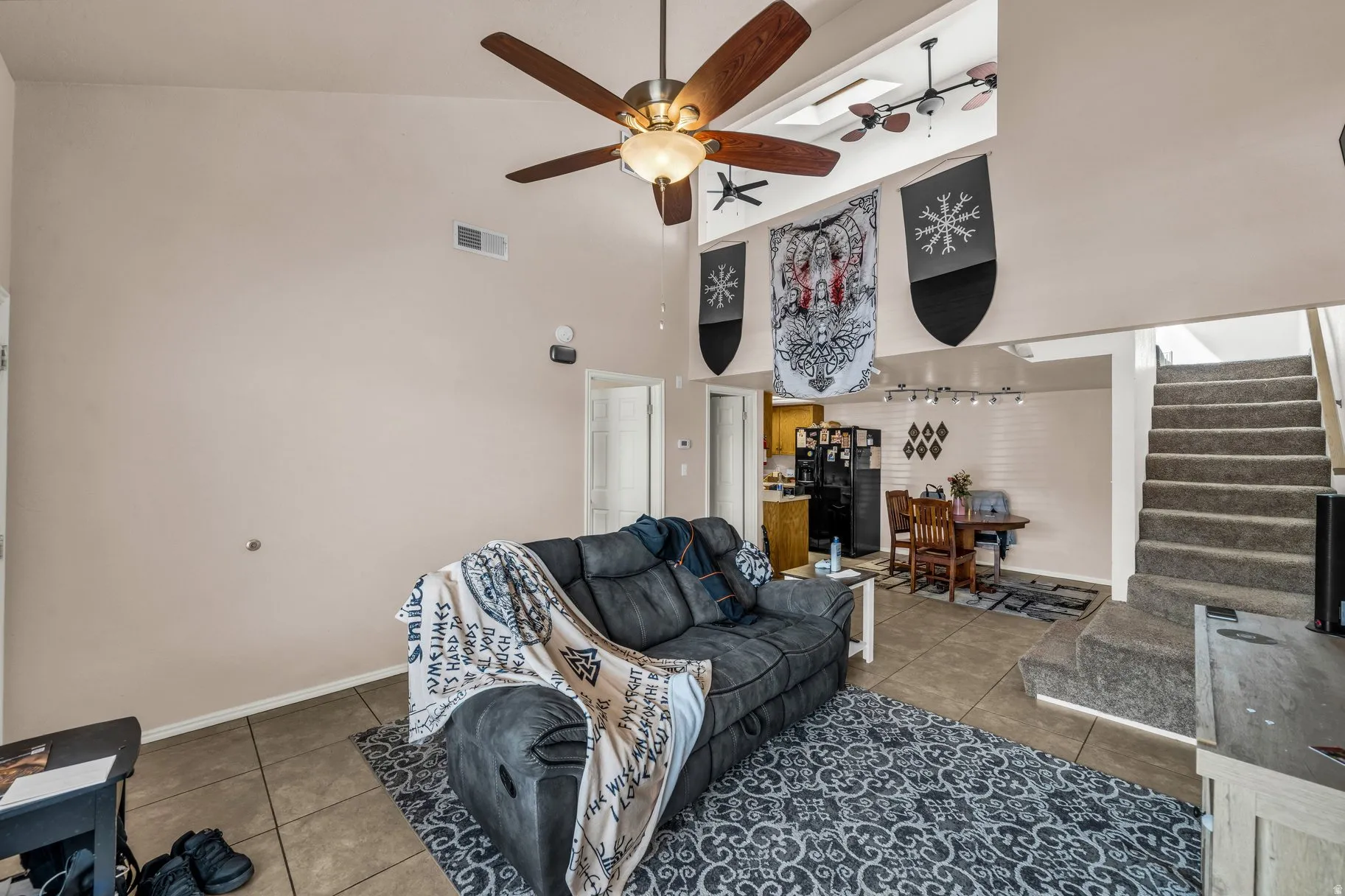 Tiled living room with a high ceiling and a ceiling fan