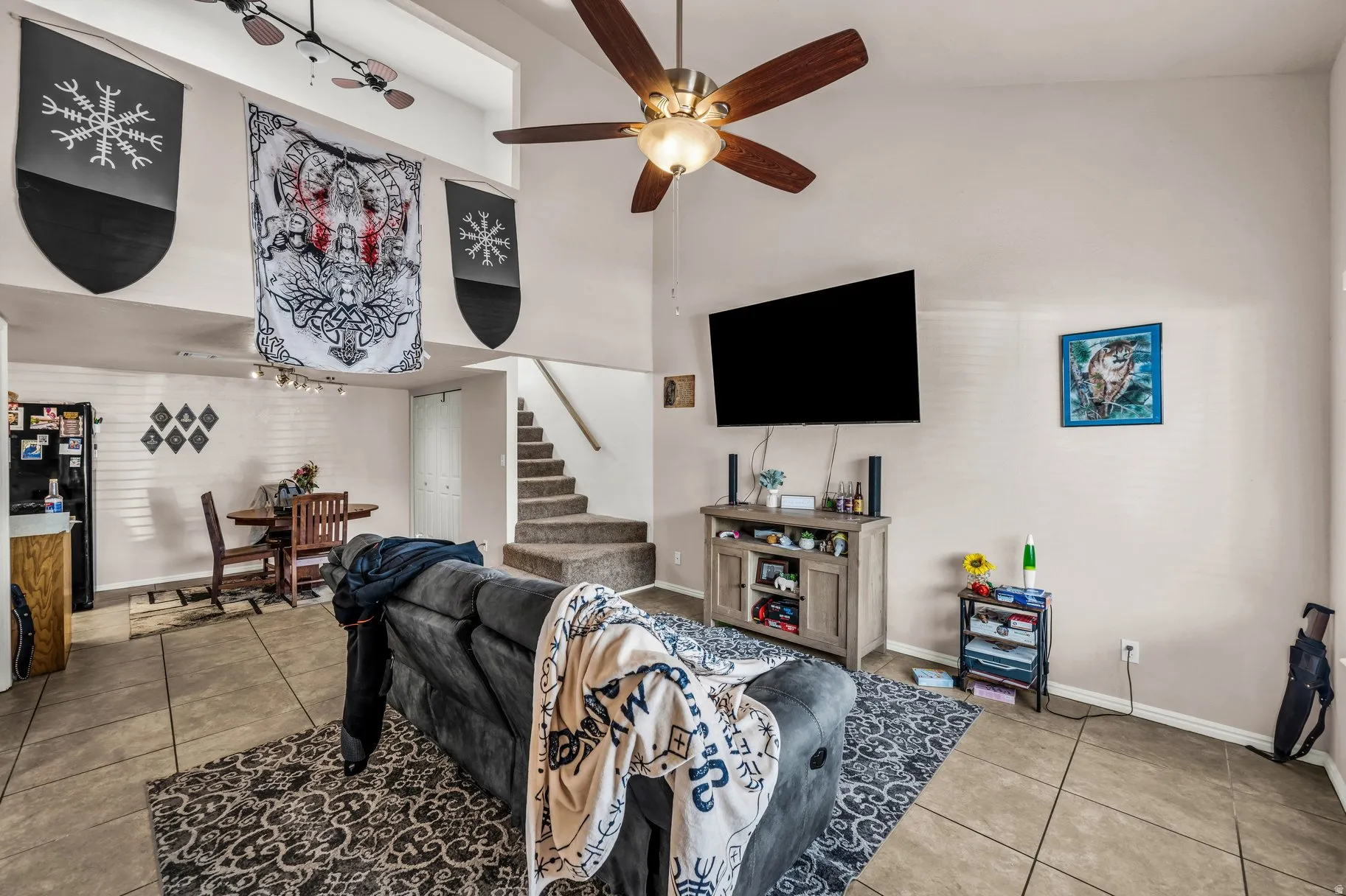 Living area featuring light tile patterned floors, ceiling fan, and a high ceiling