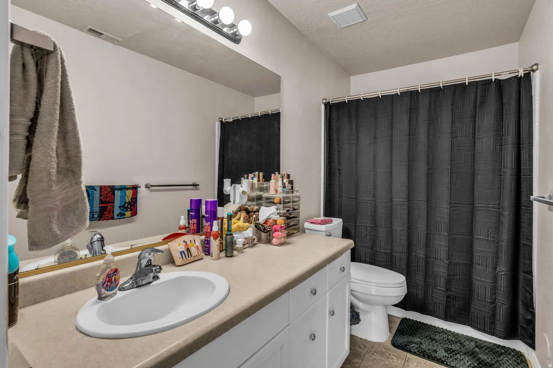 Bathroom featuring vanity, a shower with shower curtain, a textured ceiling, and light tile patterned floors