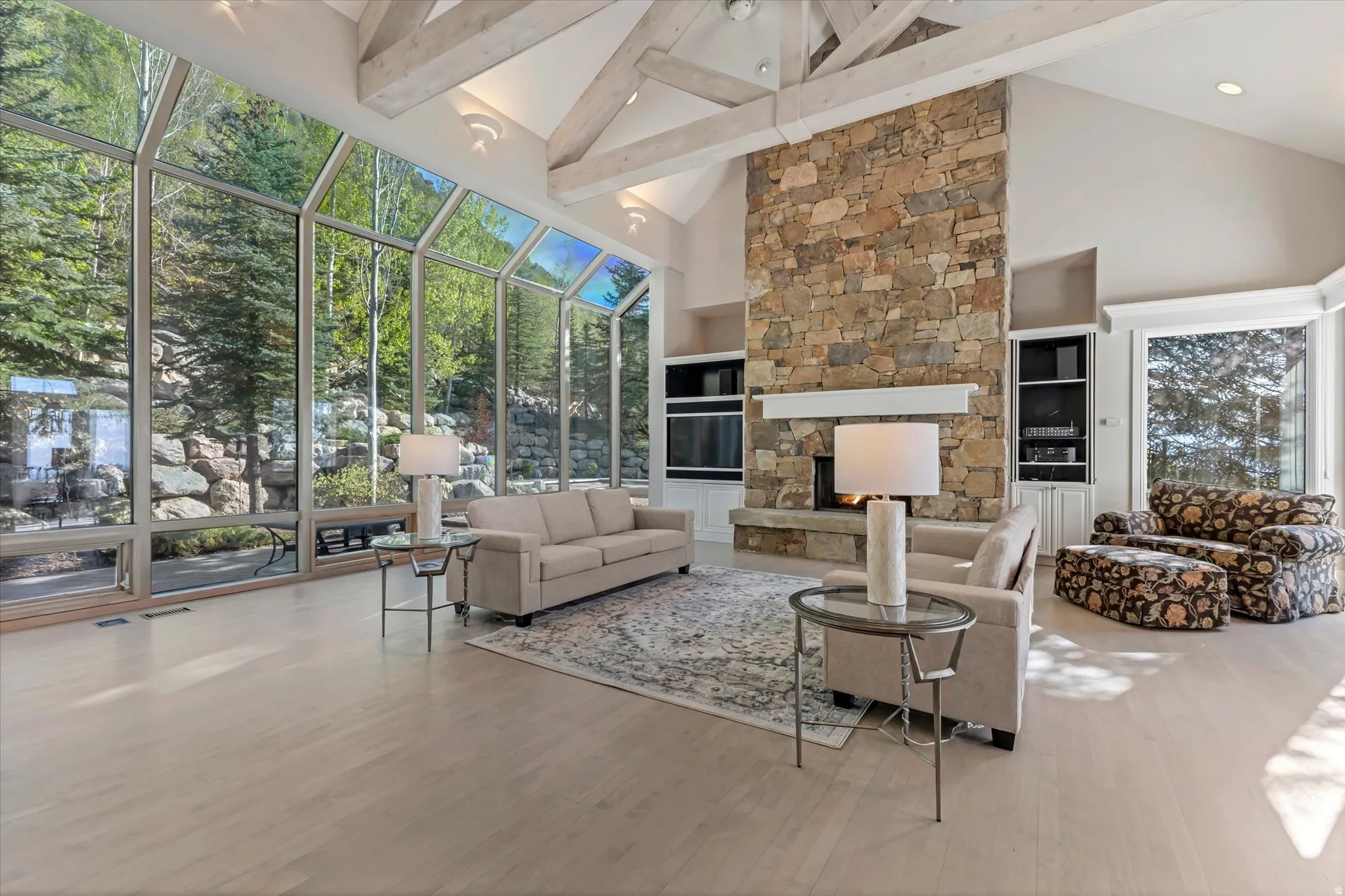 Living room with a sunroom, built in features, a fireplace, and wood finished floors