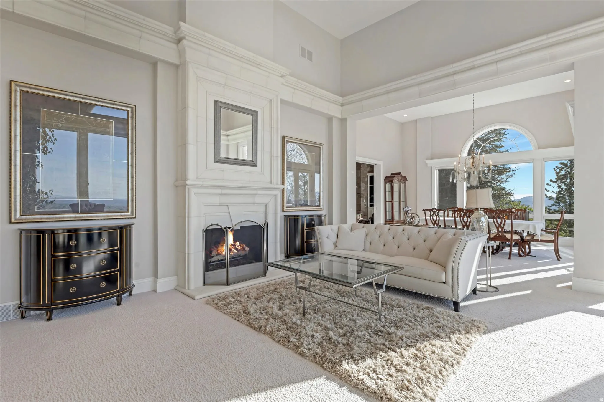 Living area featuring carpet flooring, a high ceiling, a large fireplace, and a chandelier