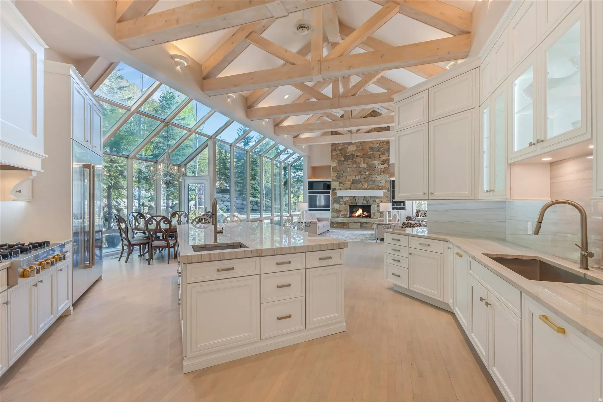 Kitchen with a stone fireplace, light wood-style floors, open floor plan, a center island, and built in refrigerator