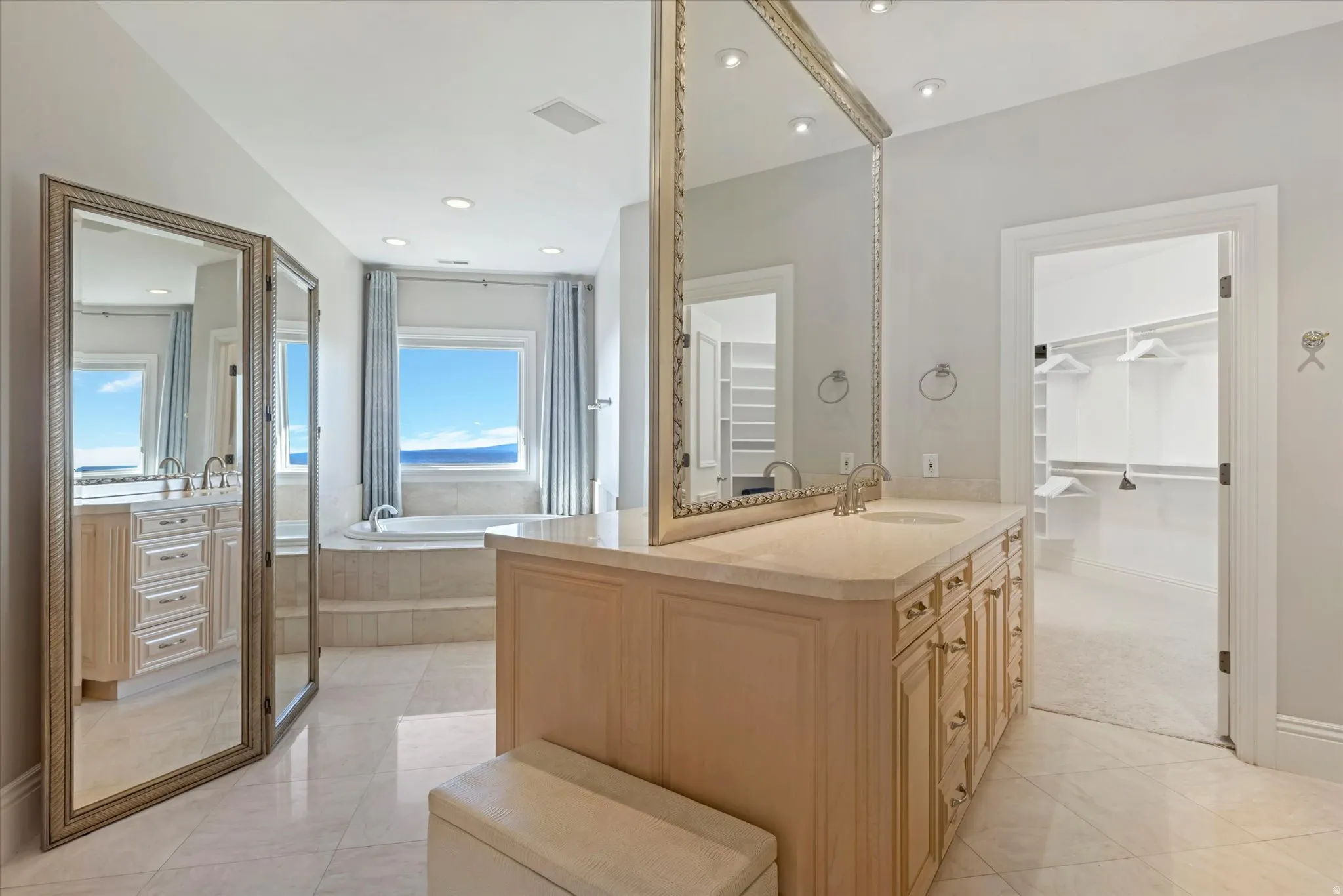 Full bath with two vanities, a garden tub, a walk in closet, light tile patterned flooring, and recessed lighting