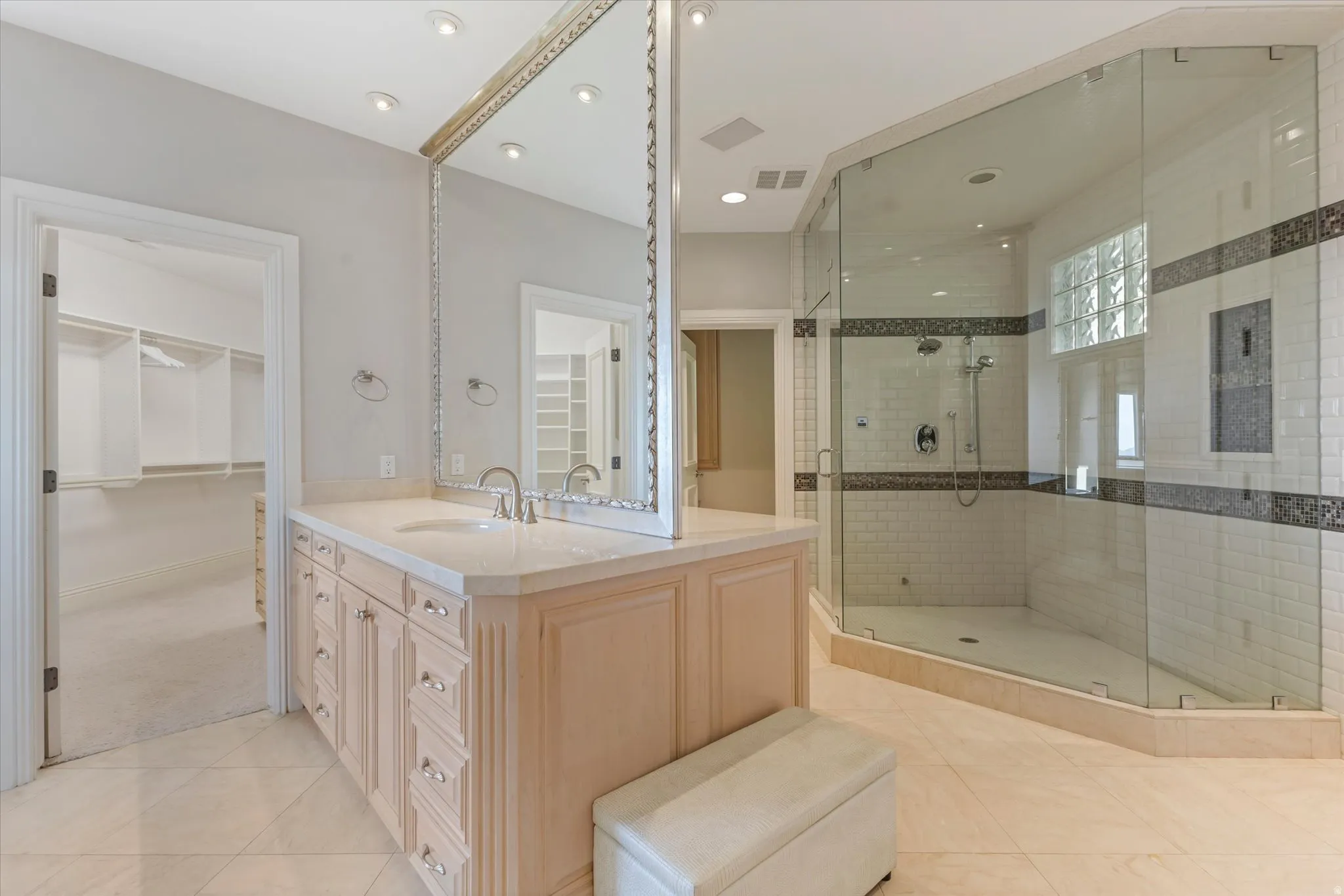 Full bathroom featuring a walk in closet, vanity, a stall shower, and light tile patterned floors