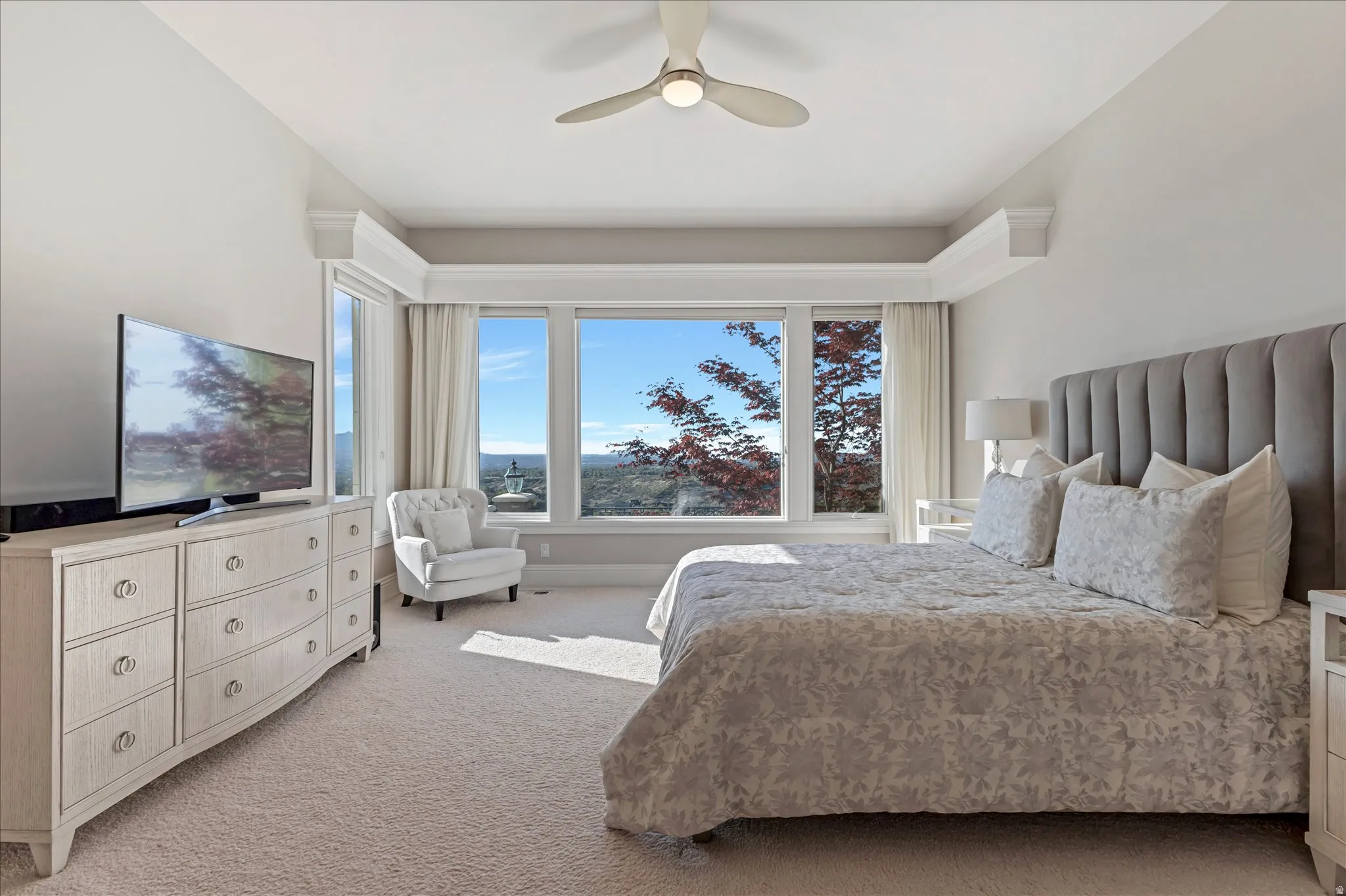 Bedroom with light carpet, multiple windows, and ceiling fan