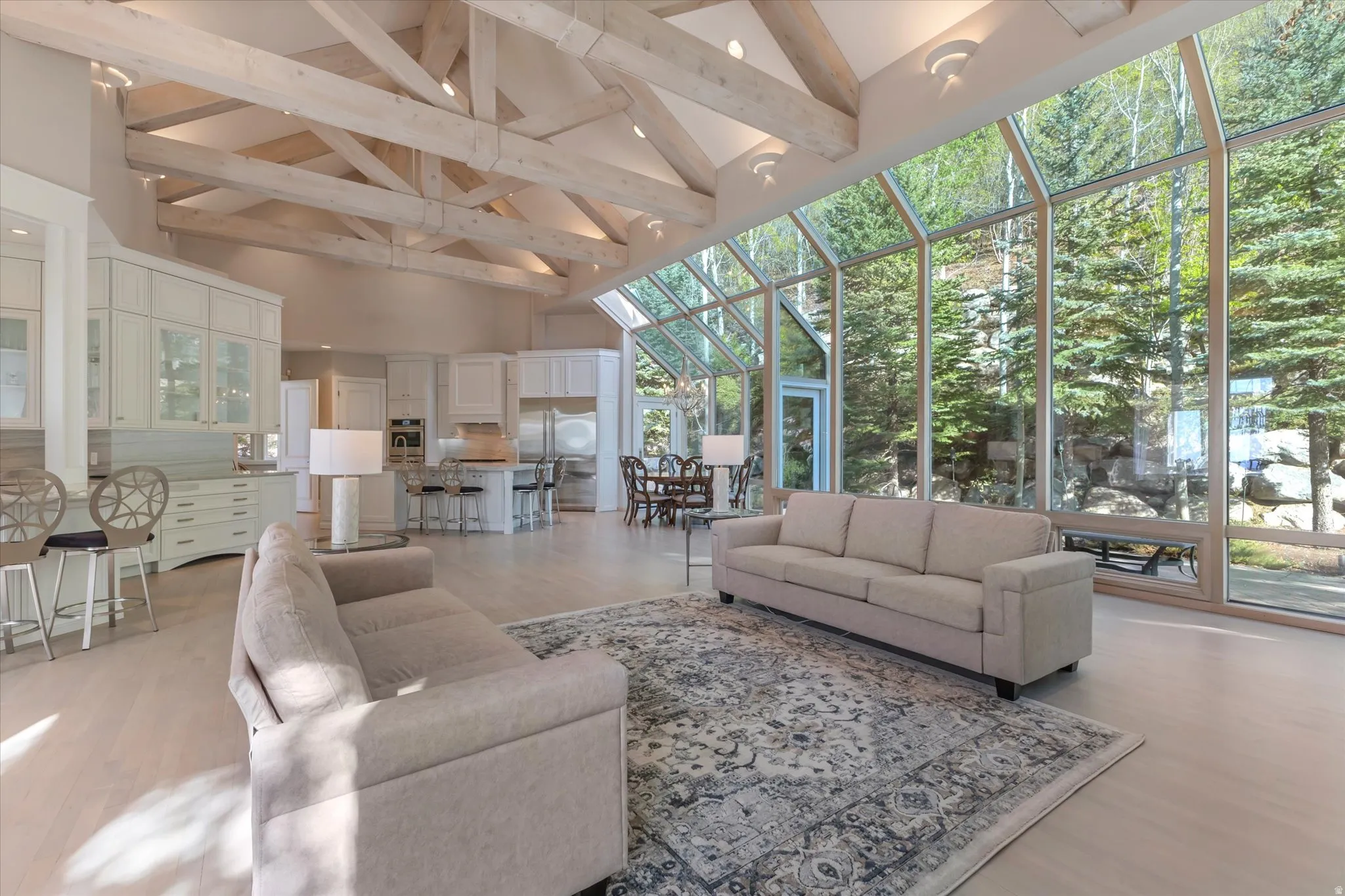 Living room with a sunroom, light wood-type flooring, and floor to ceiling windows