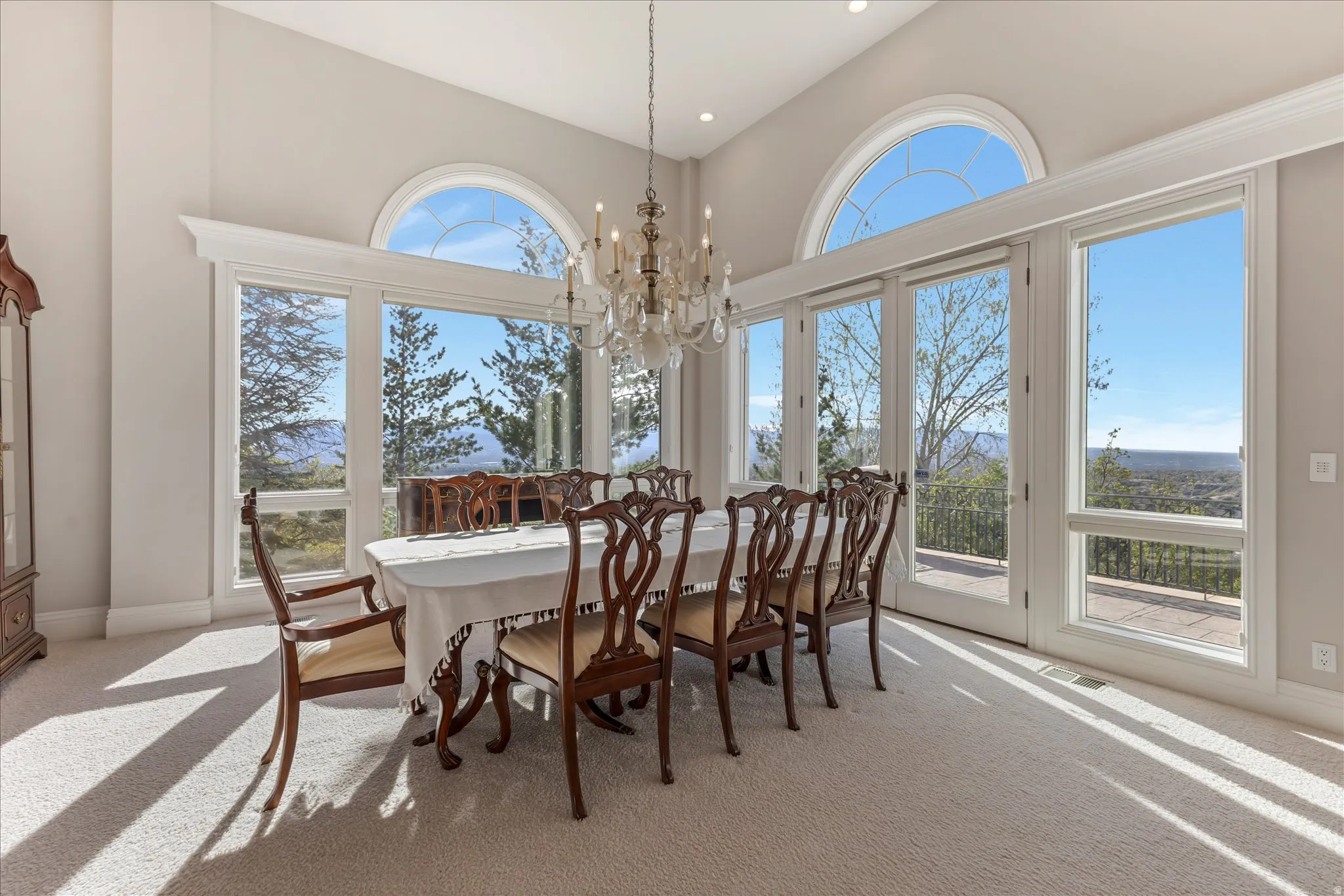 Dining room with a chandelier, light carpet, and a high ceiling