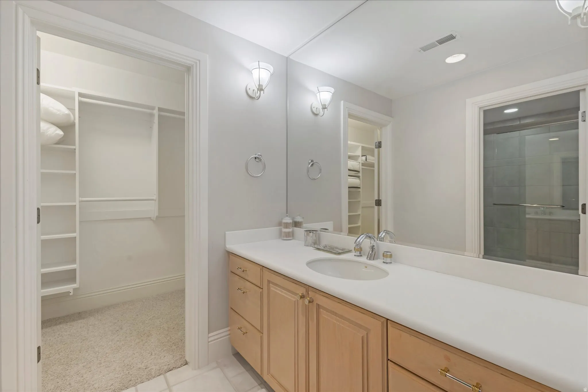 Bathroom featuring a spacious closet, vanity, light colored carpet, and recessed lighting