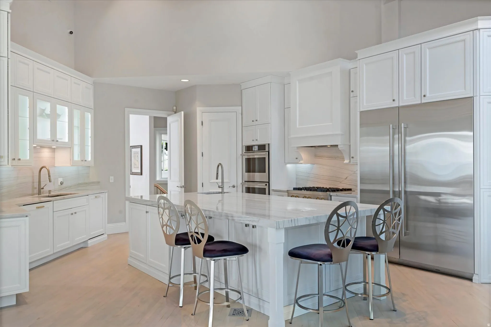 Kitchen with backsplash, stainless steel appliances, light wood finished floors, light stone counters, and recessed lighting