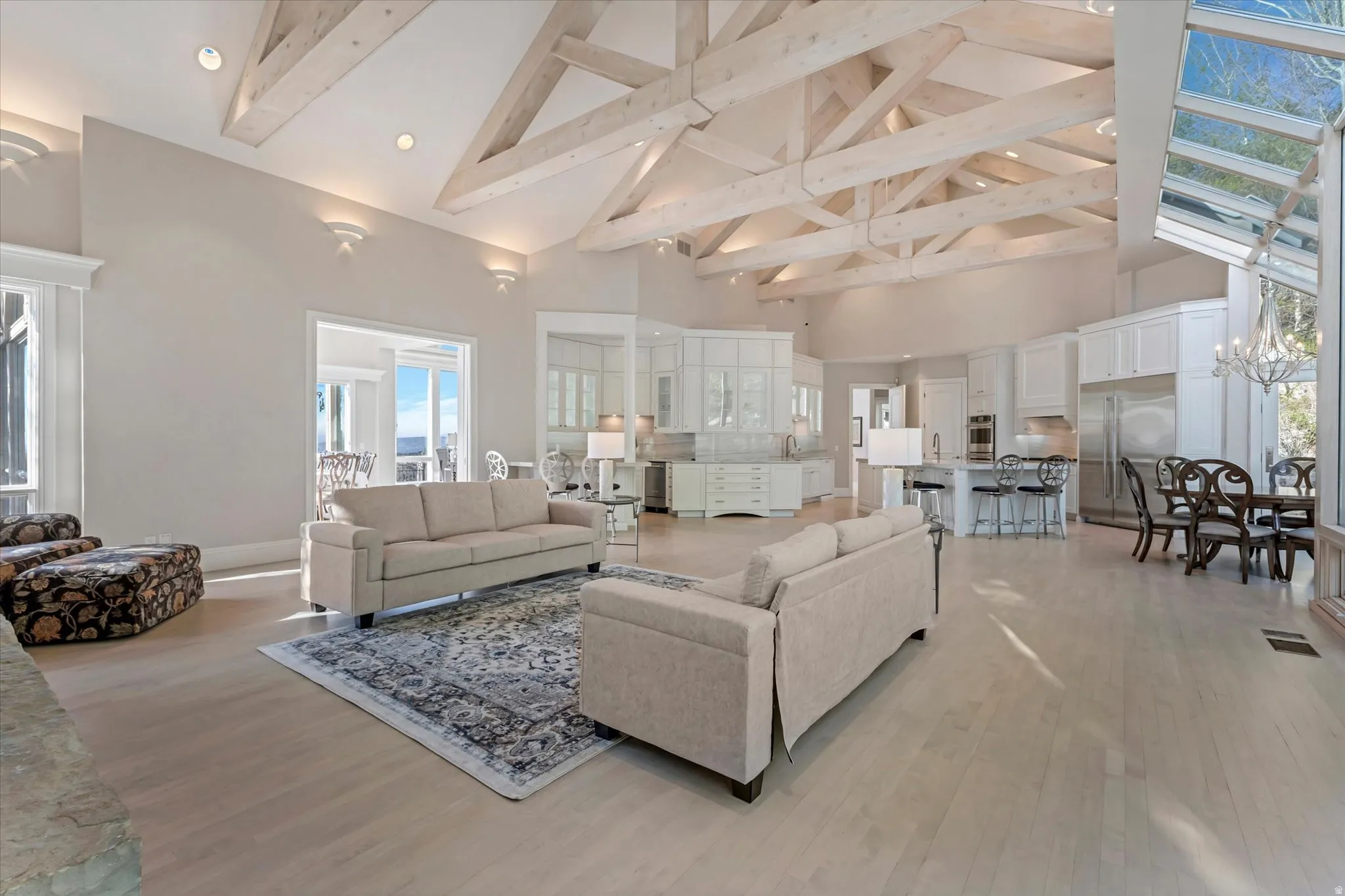 Living room with light wood finished floors, wine cooler, and suspended lighting