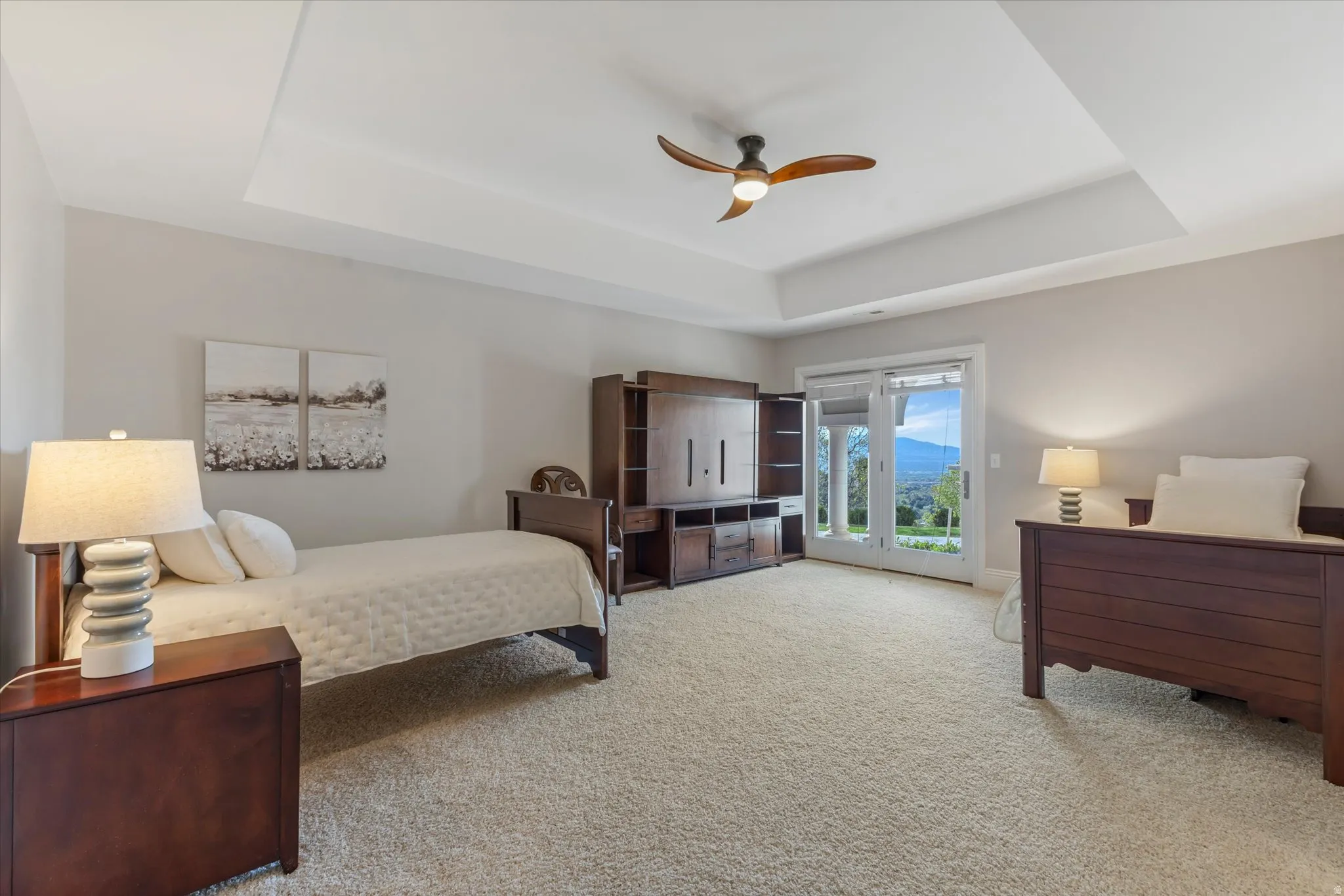 Bedroom with access to exterior, light carpet, ceiling fan, and a tray ceiling