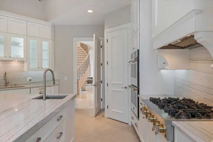 Kitchen featuring decorative backsplash, white cabinets, stainless steel appliances, and recessed lighting