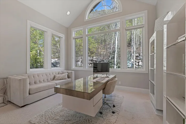 Home office with light carpet and lofted ceiling