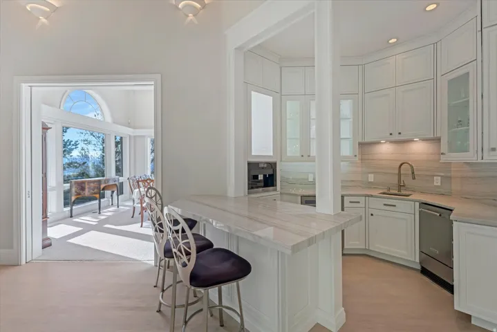 Kitchen featuring white cabinets, tasteful backsplash, a kitchen bar, a peninsula, and light wood finished floors