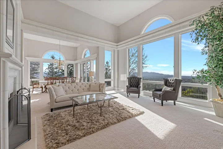 Living room with carpet floors, healthy amount of natural light, a high ceiling, a mountain view, and suspended lighting