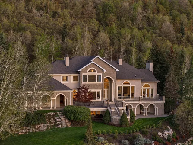 View of front of house featuring a chimney, a front yard, stucco siding, and a balcony