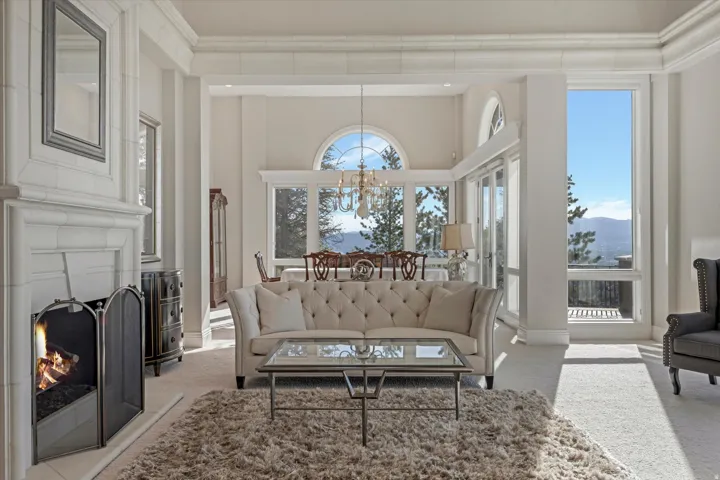Living room featuring light colored carpet, a large fireplace, a chandelier, and a high ceiling