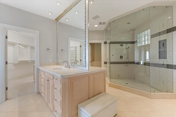 Full bathroom featuring a walk in closet, vanity, a stall shower, and light tile patterned floors