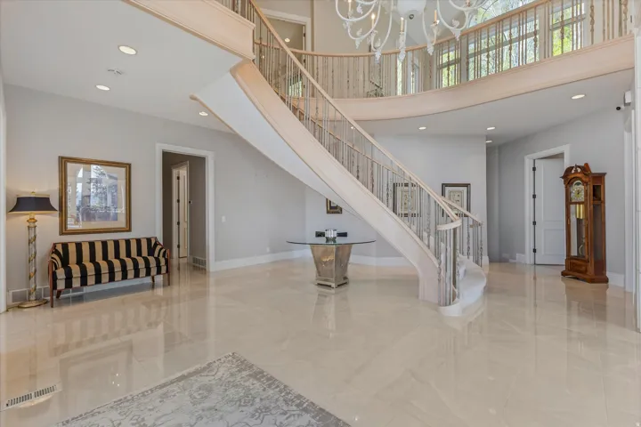 Staircase featuring a high ceiling, a chandelier, and marble finish floors