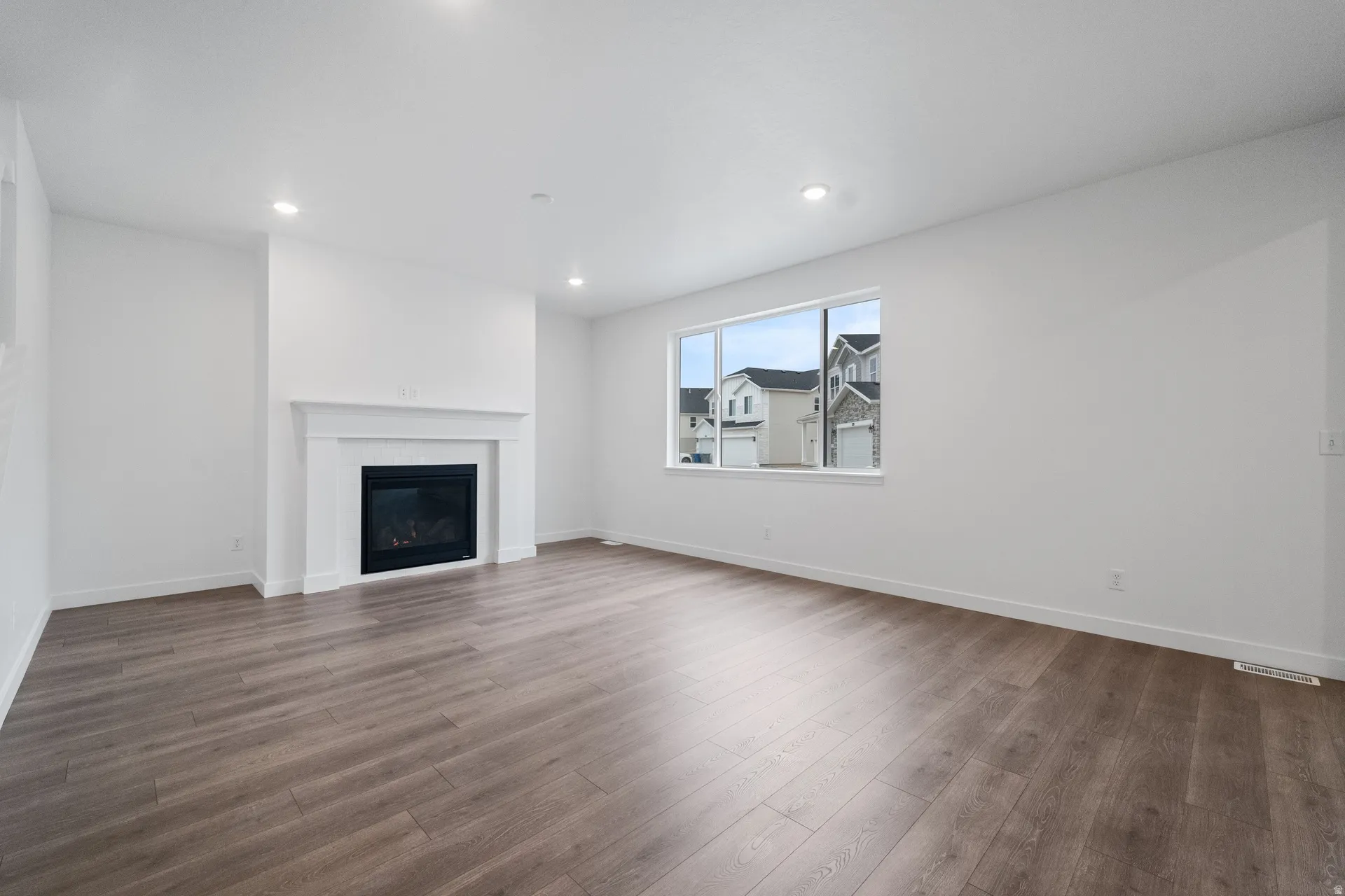 Unfurnished living room with dark wood finished floors, a glass covered fireplace, and recessed lighting