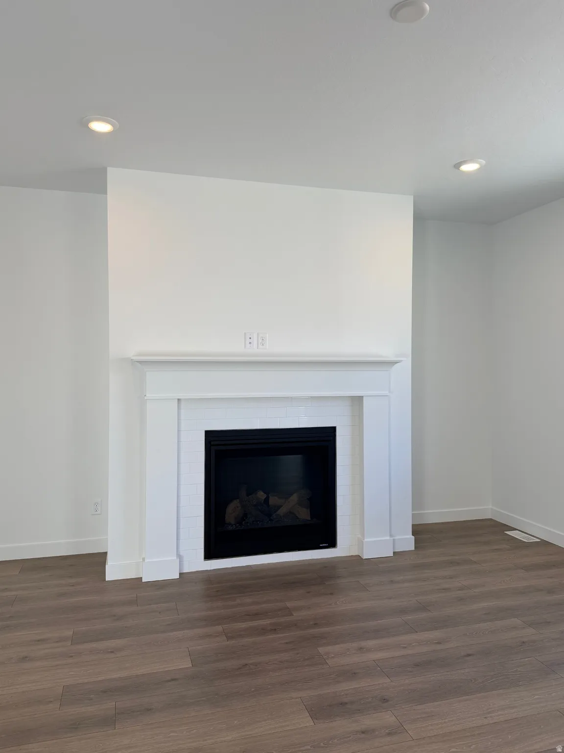 Detailed view of a fireplace, wood finished floors, and recessed lighting