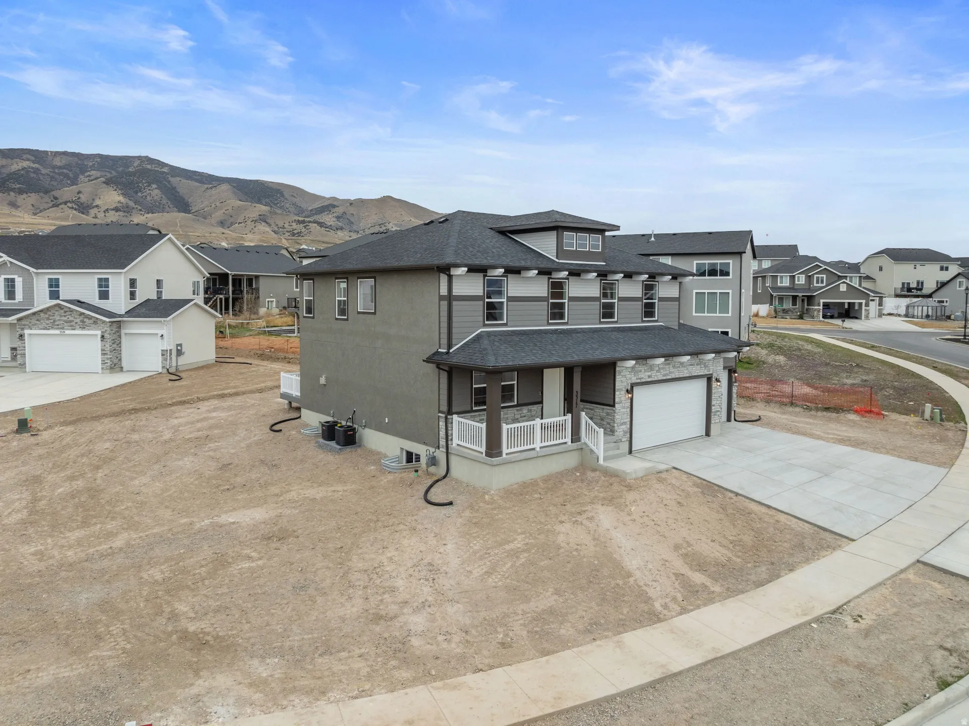 View of front of house with a porch, concrete driveway, a residential view, a shingled roof, and stone siding