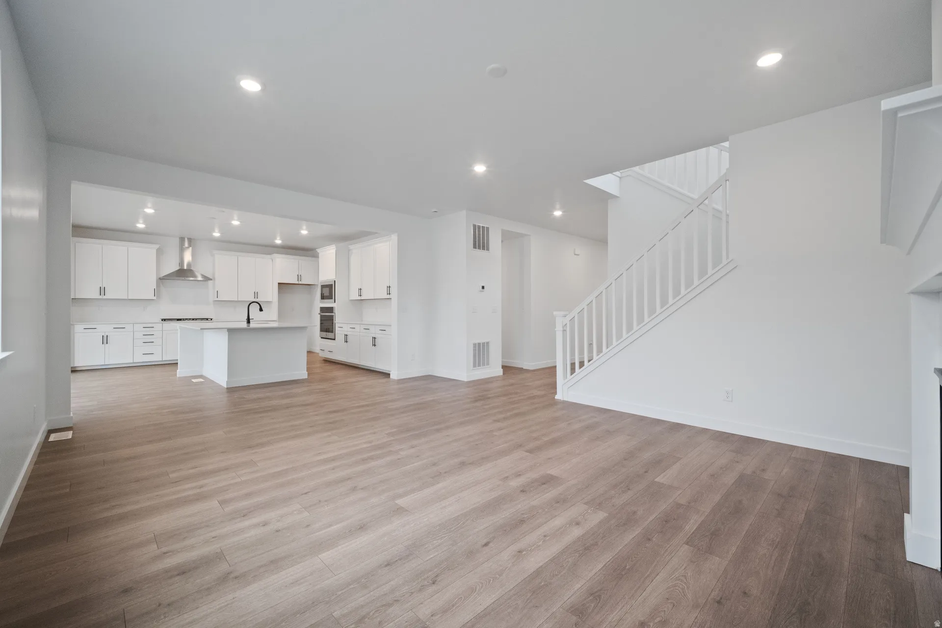 Living room with light wood-type flooring and recessed lighting