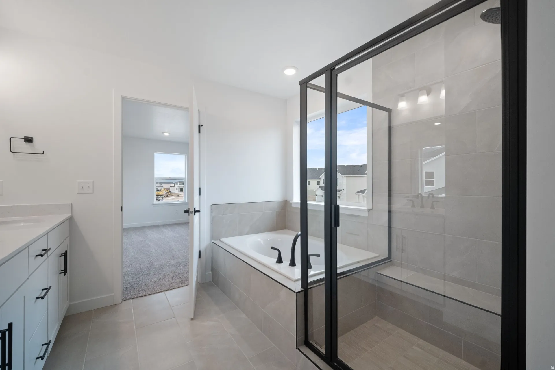 Primary bathroom featuring a vanity, light tile floors, a bath, and recessed lighting