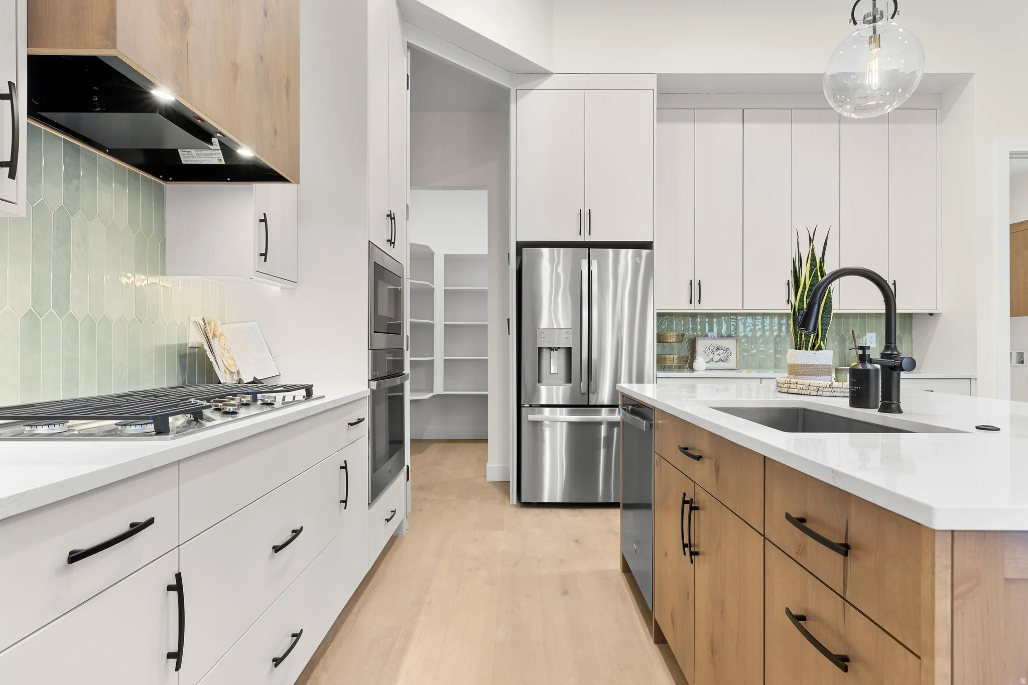 Modern kitchen featuring light wood-finish flooring and a light-toned island with a built-in sink