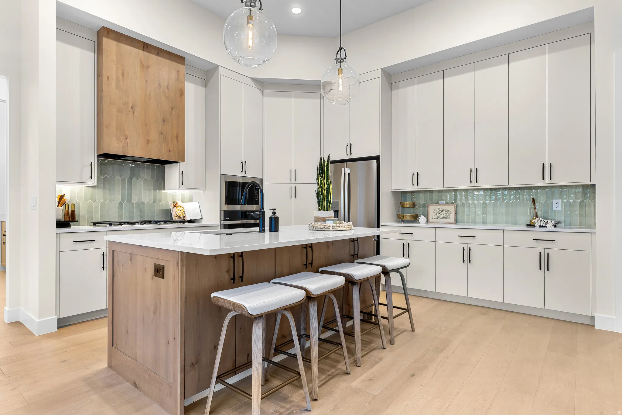 Contemporary kitchen featuring a large central island, white shaker-style cabinetry, and light wood-finish flooring