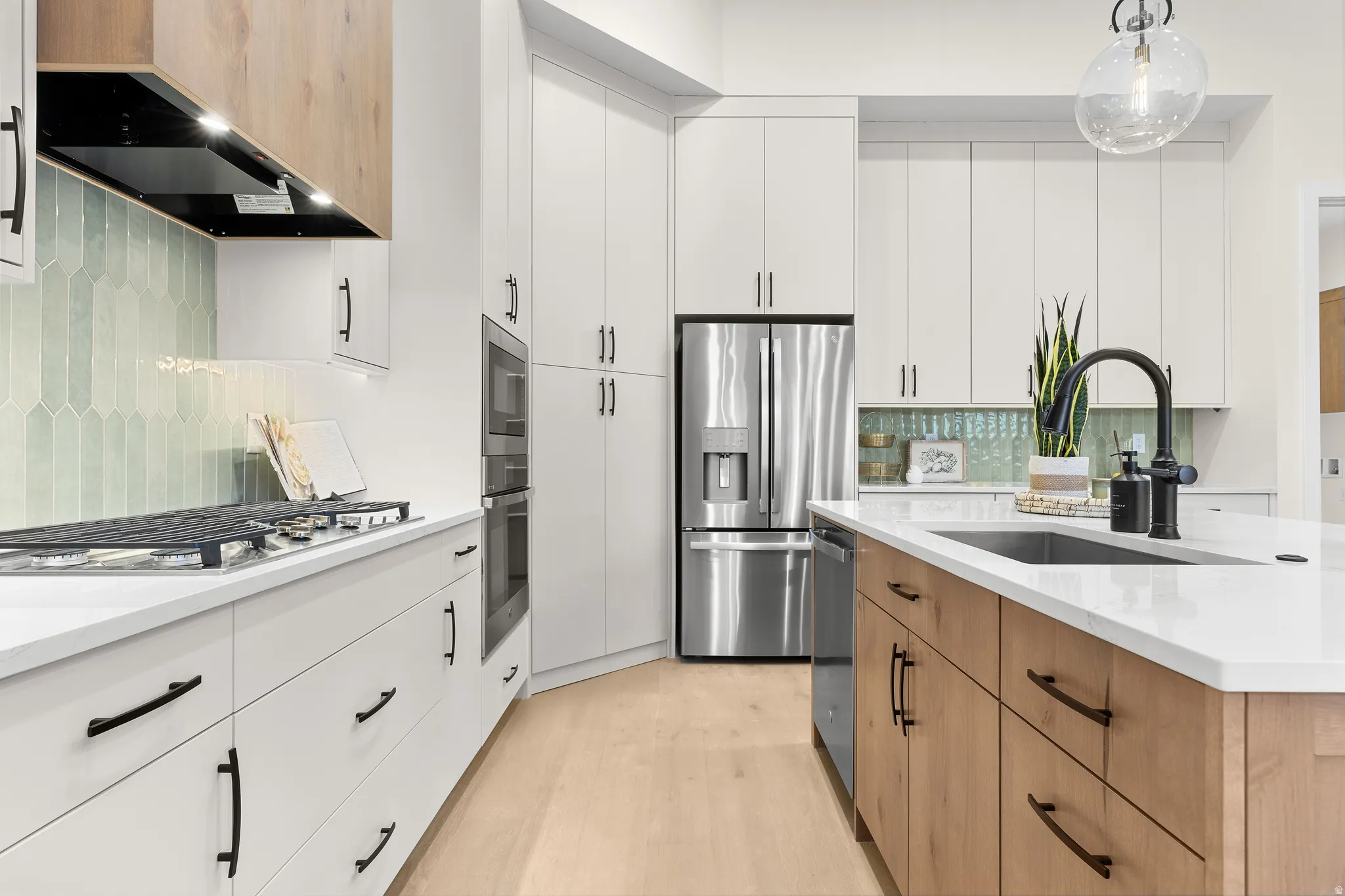 Modern kitchen featuring white cabinetry, a wood-finish island, stainless steel appliances, a gas cooktop, and a distinctive pale green picket tile backsplash