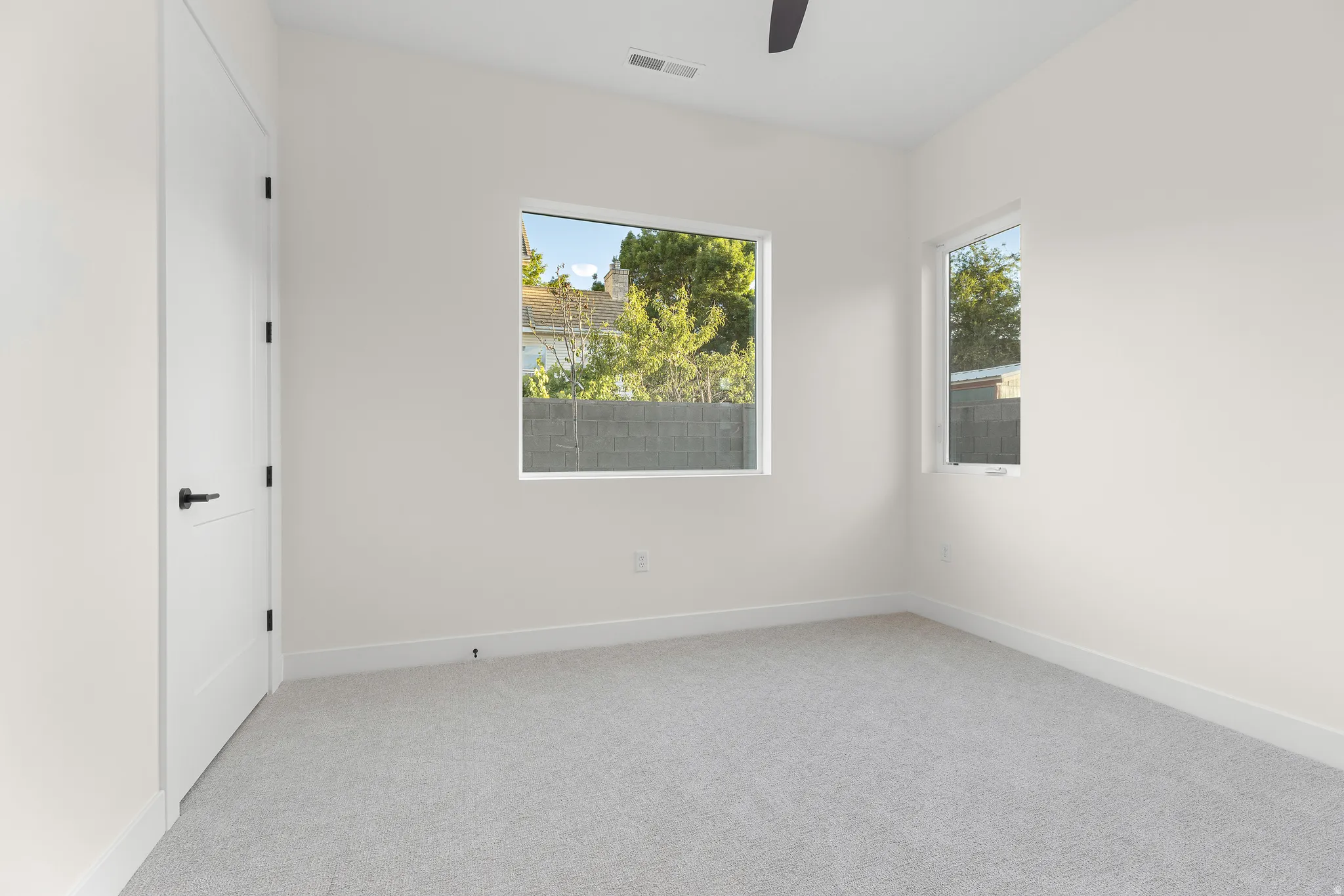 Unfurnished room featuring light colored carpet, healthy amount of natural light, and a ceiling fan