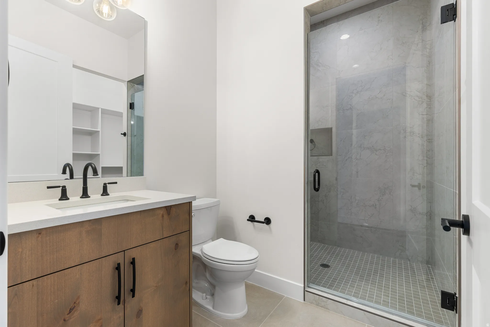 Bathroom featuring vanity, a marble finish shower, and light tile patterned floors