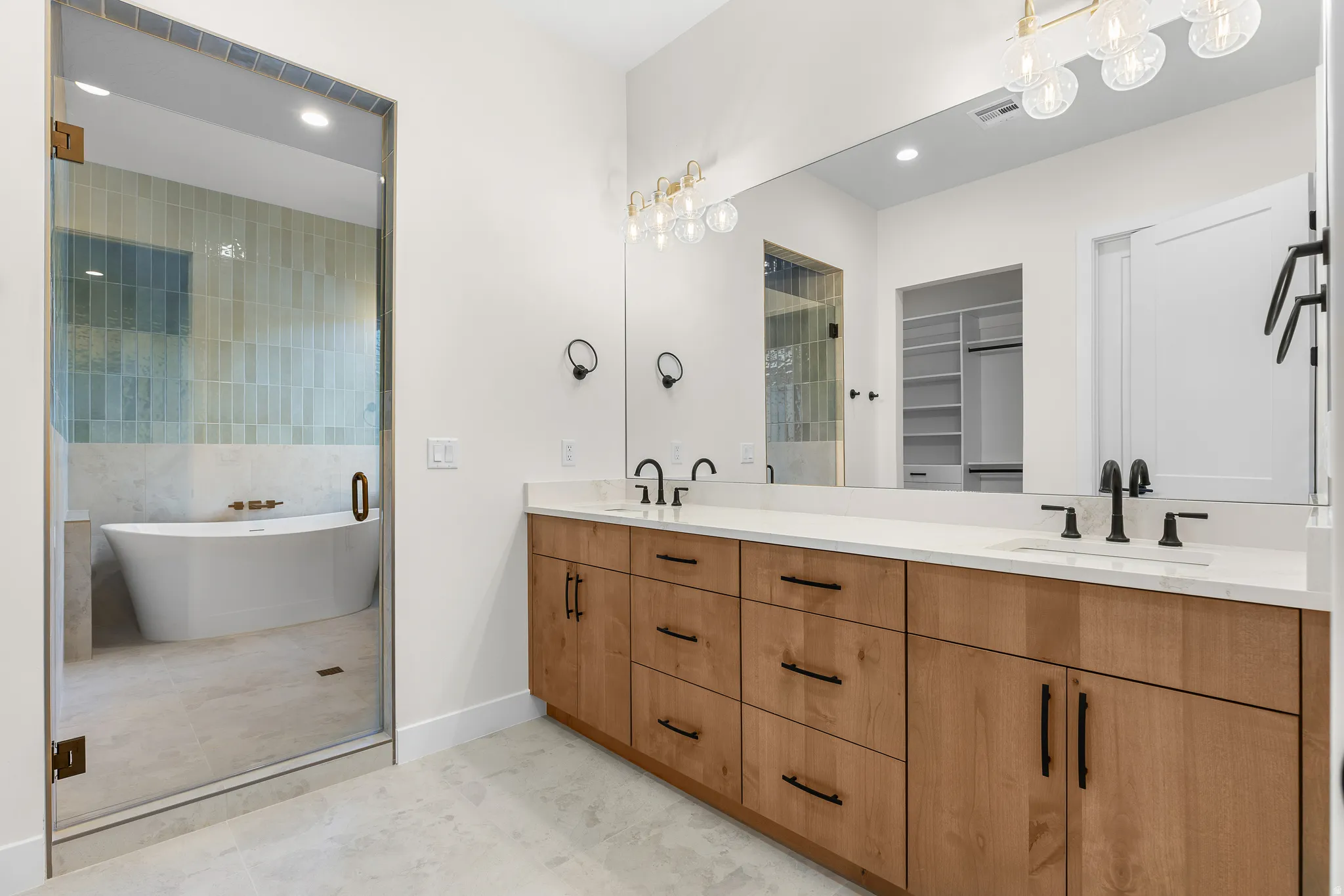 Full bath with double vanity, a freestanding tub, a spacious closet, recessed lighting, and light tile patterned floors