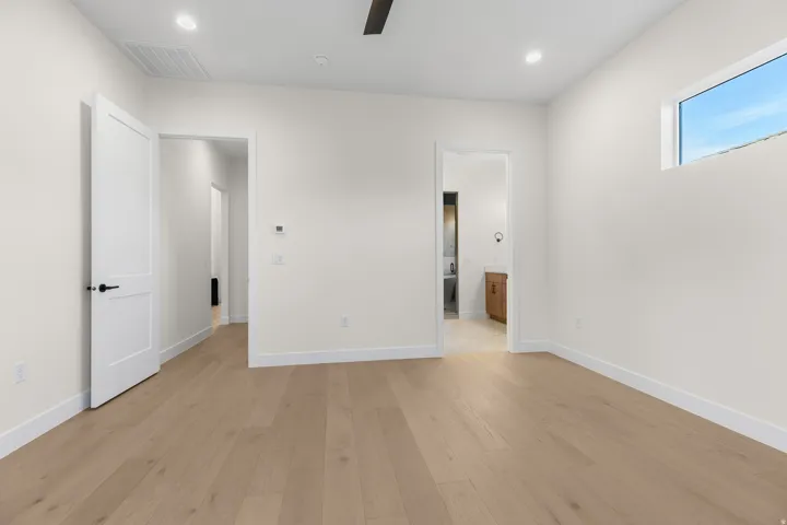Unfurnished bedroom with light wood finished floors, ensuite bath, ceiling fan, and recessed lighting