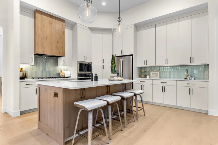 Contemporary kitchen featuring a large central island, white shaker-style cabinetry, and light wood-finish flooring
