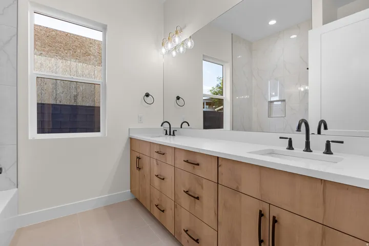 Bathroom featuring double vanity, light tile patterned floors, a shower, and a tub