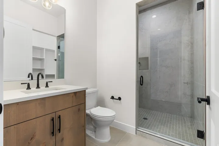 Bathroom featuring vanity, a marble finish shower, and light tile patterned floors